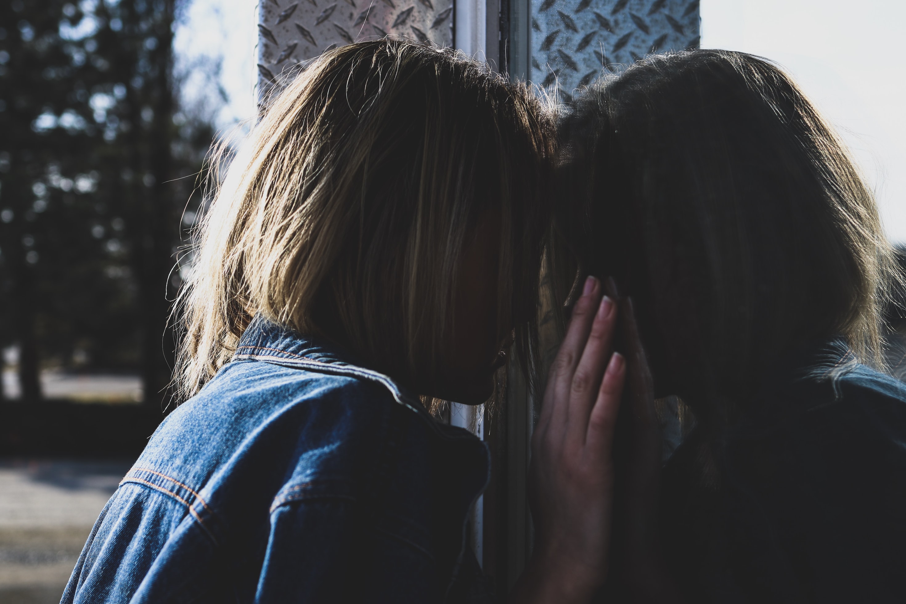 Photo of a girl standing in front of her reflection in a window